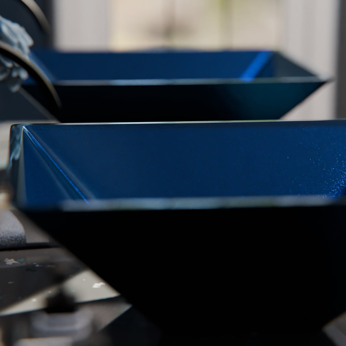 Blue foiled square tempered glass vessel sink by Novatto, modern bathroom fixture with sleek dark blue finish.