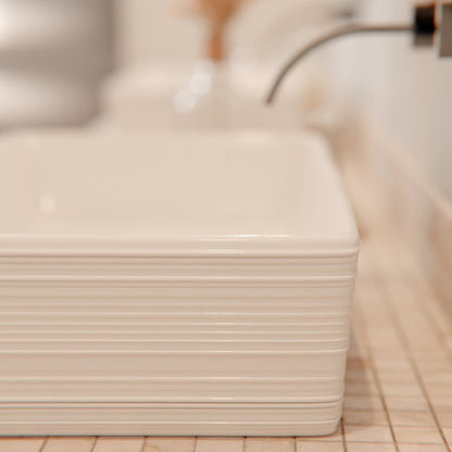 White porcelain vessel sink with rectangular shape and grooved exterior, designed by Novatto.