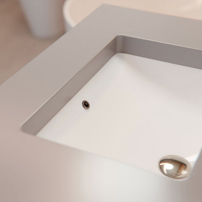 White rectangular undermount porcelain vessel sink with overflow, designed by Novatto, shown in the image.