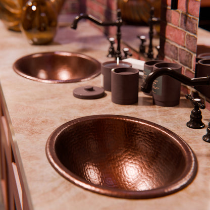 Oval rolled rim copper drop-in bathroom sink by Novatto with antique finish, shown in a traditional bathroom setting.