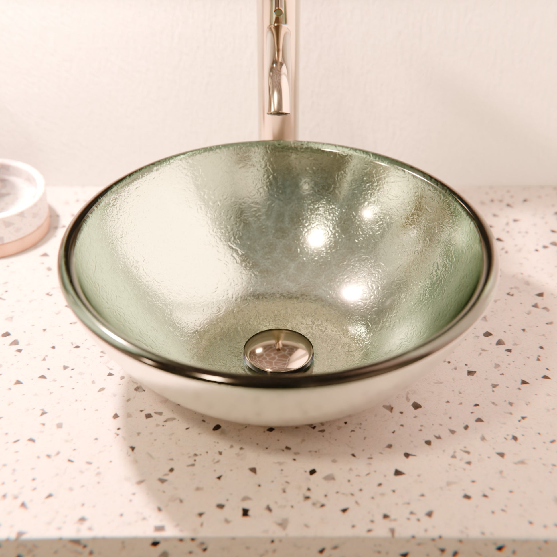 Silver foiled round tempered glass vessel bathroom sink by Novatto with modern design, shown with matching faucet and mint accents.