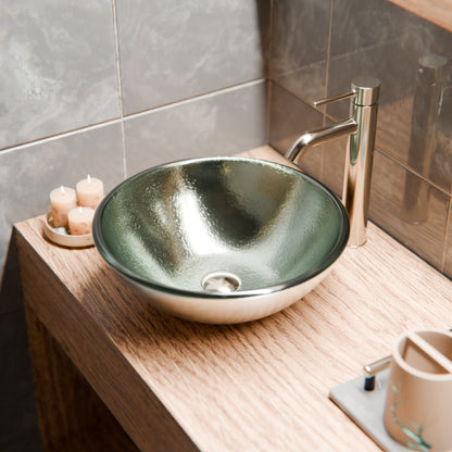 Silver foiled round tempered glass vessel bathroom sink by Novatto with a modern design, shown on a wooden surface.