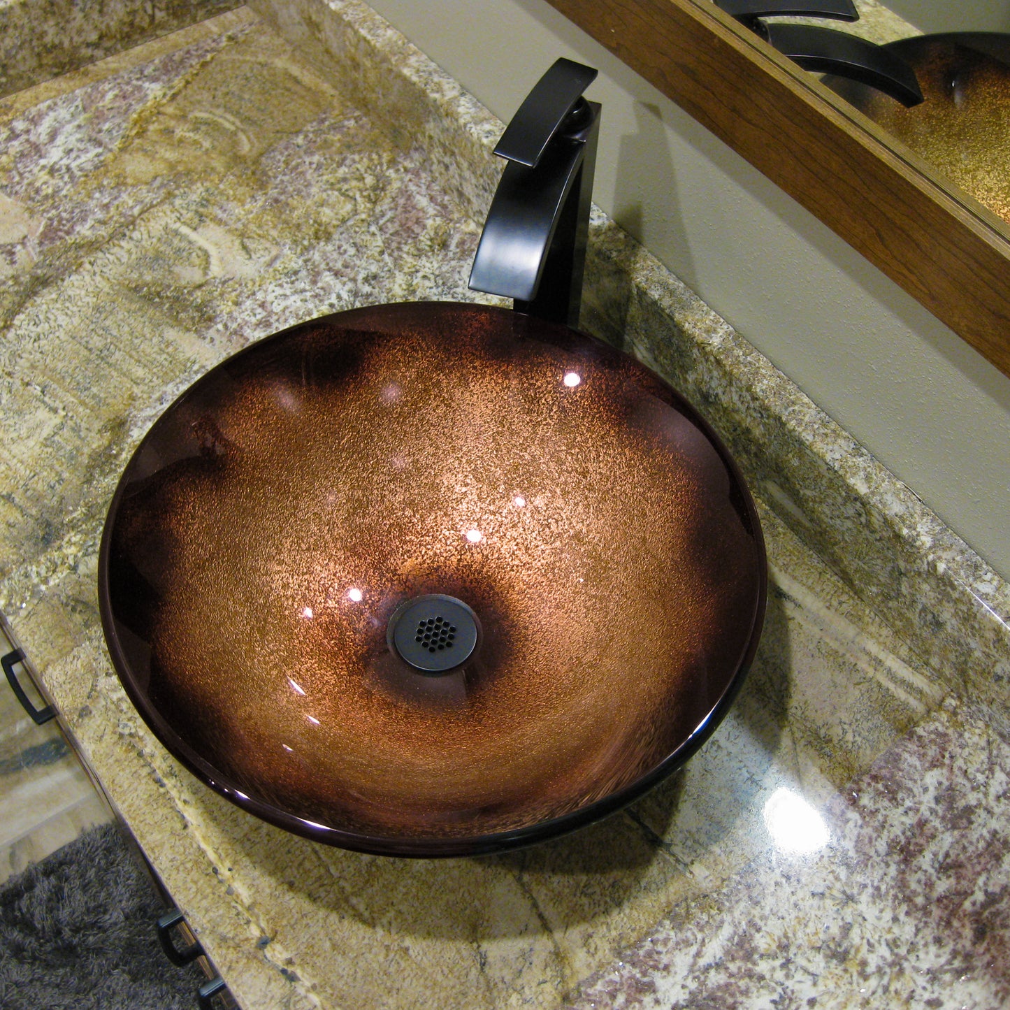 Black and copper round glass vessel bathroom sink by Novatto, featuring a transitional style with a sleek, modern design.