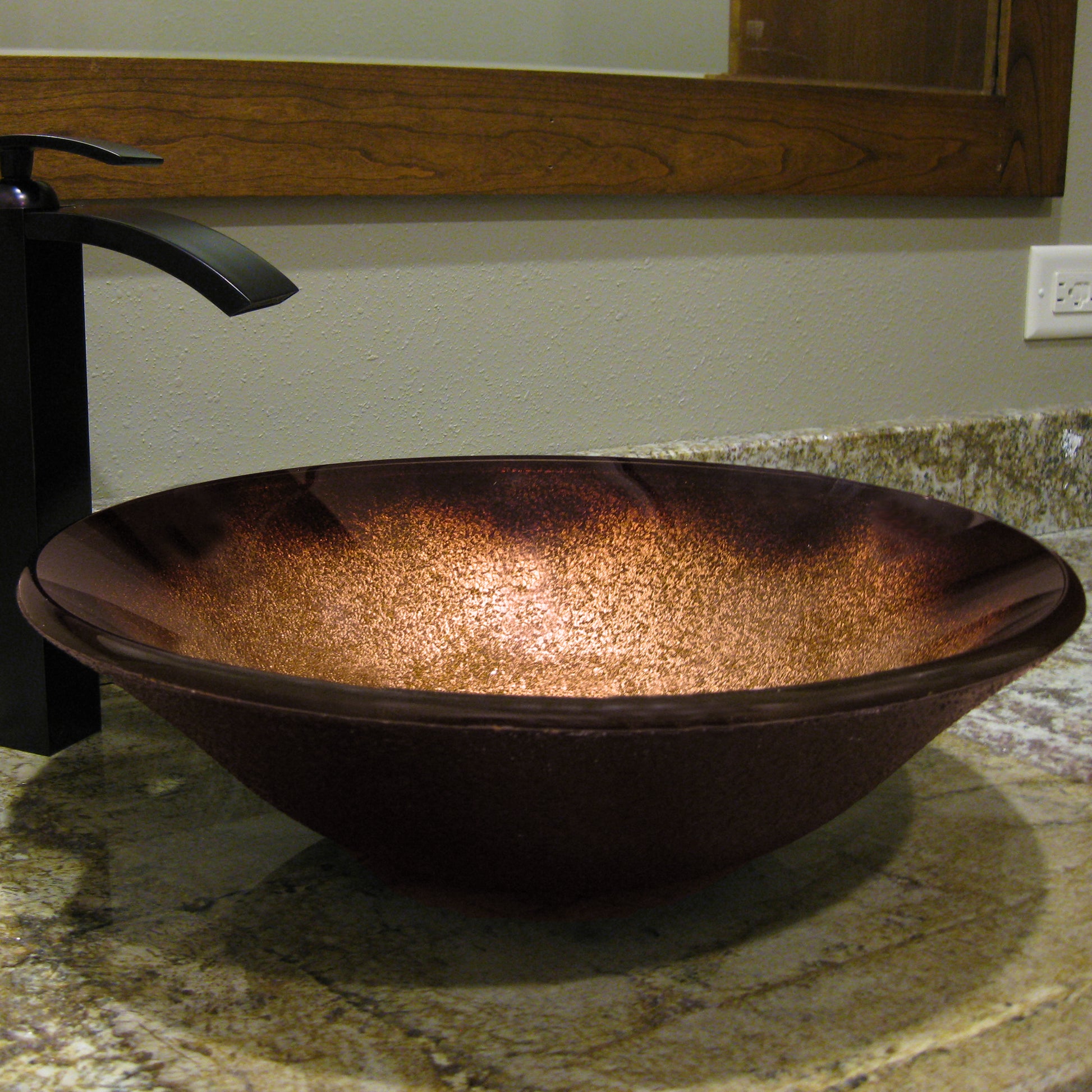 Black and copper round glass vessel bathroom sink by Novatto, showcasing its sleek transitional design and smooth glass surface.