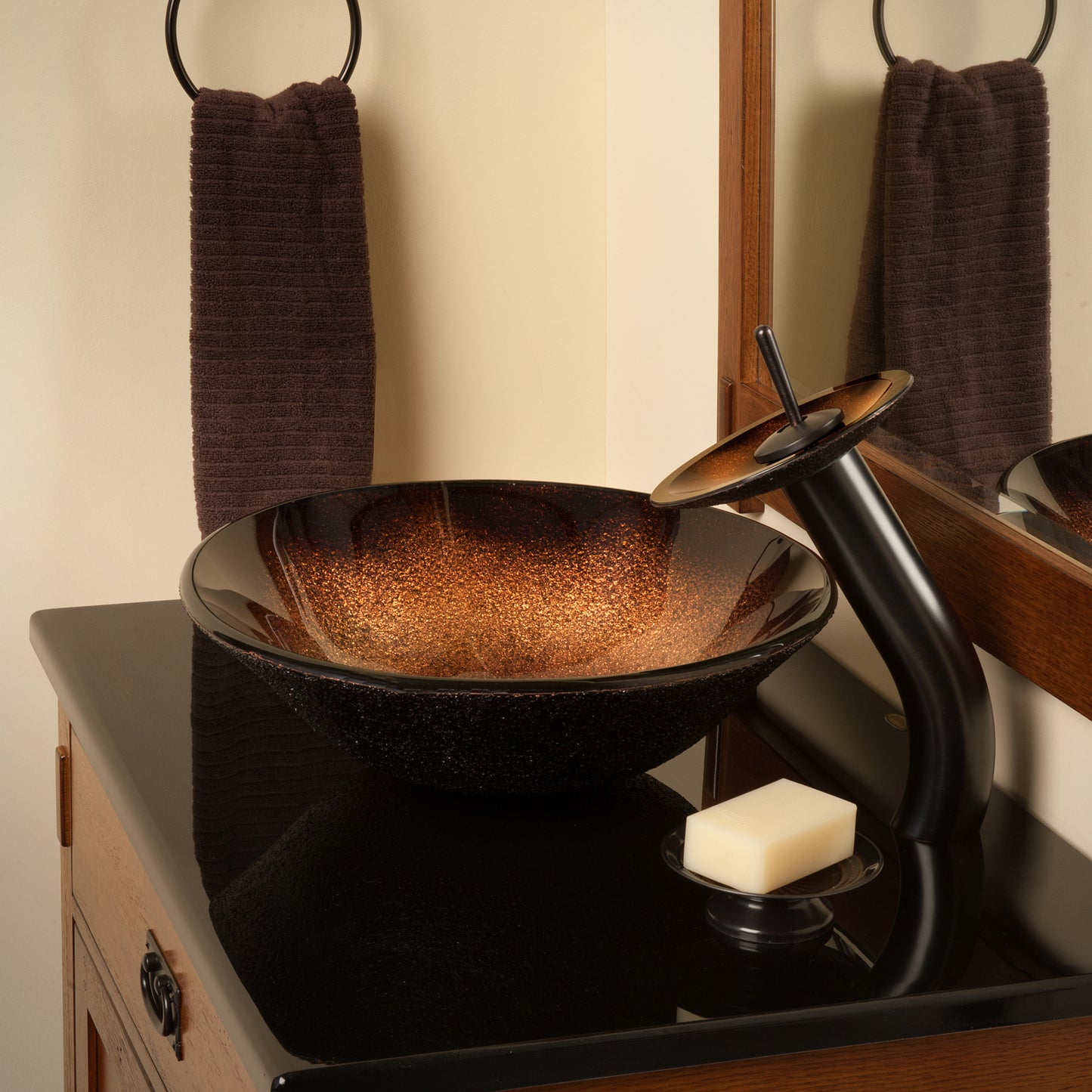 Black and copper round glass vessel bathroom sink by Novatto, with a sleek transitional design and modern copper accents.