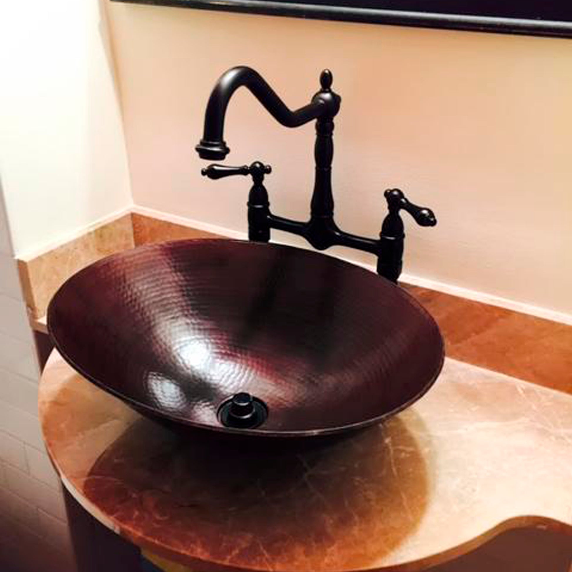 Traditional oval hammered copper vessel bath sink in antique finish by Novatto, shown in a bathroom setting.