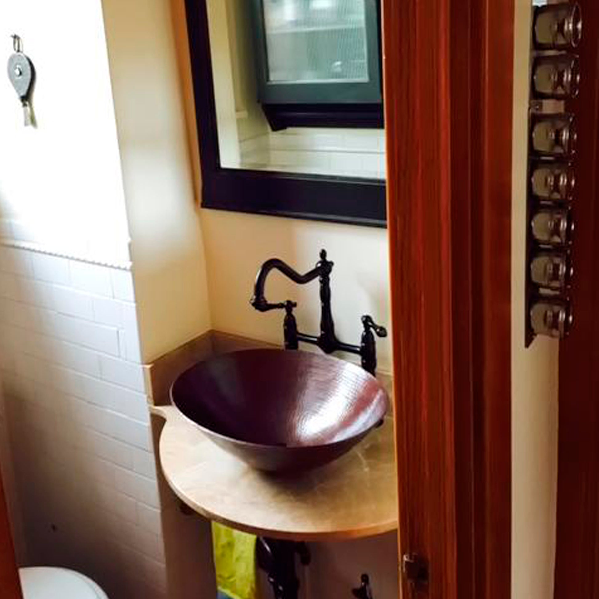 Traditional oval hammered copper vessel bathroom sink in antique finish by Novatto, shown in a stylish bathroom setting.